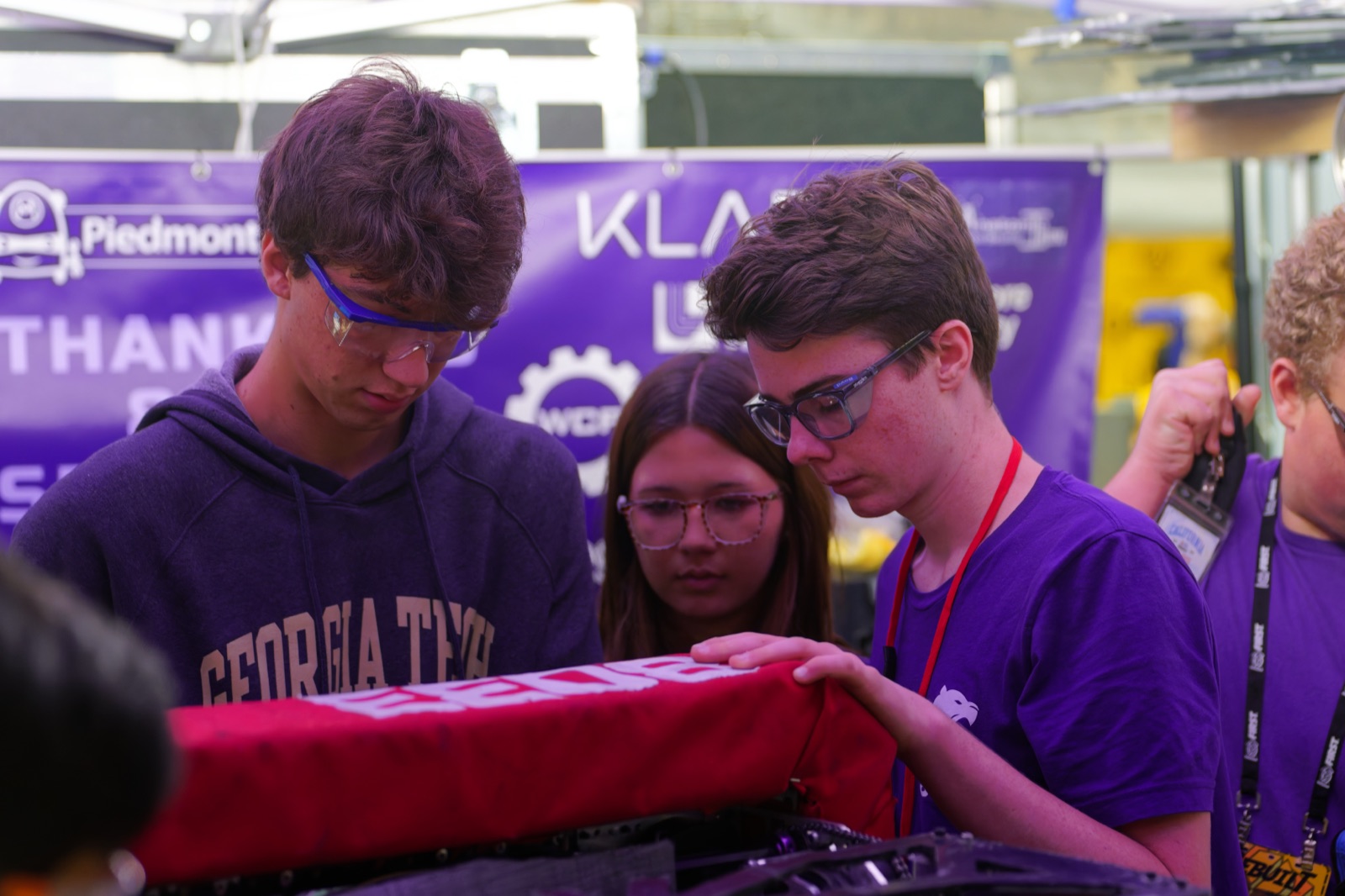 Three Highlander Robotics pit crew members working in close quarters between matches.