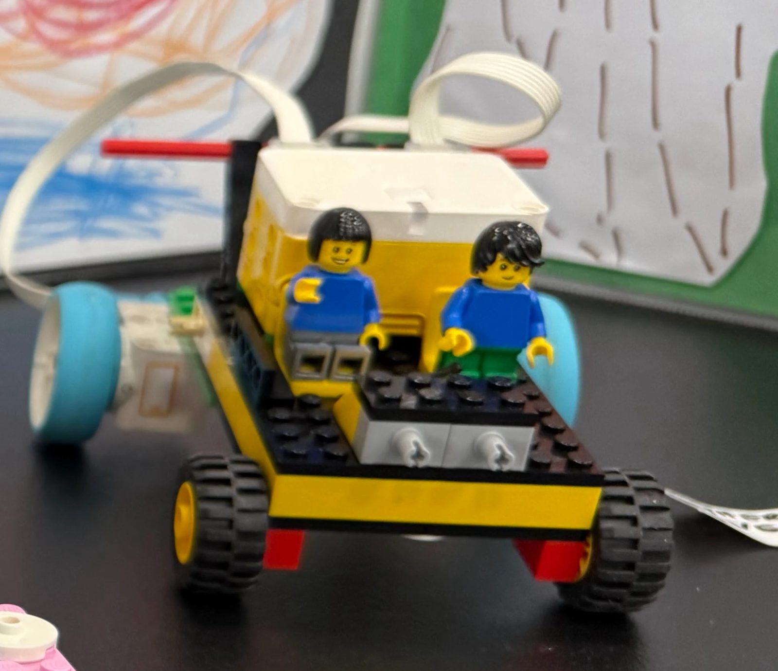 A LEGO SPIKE-built vehicle with two minifigure riders, built during a Piedmont Makers session.